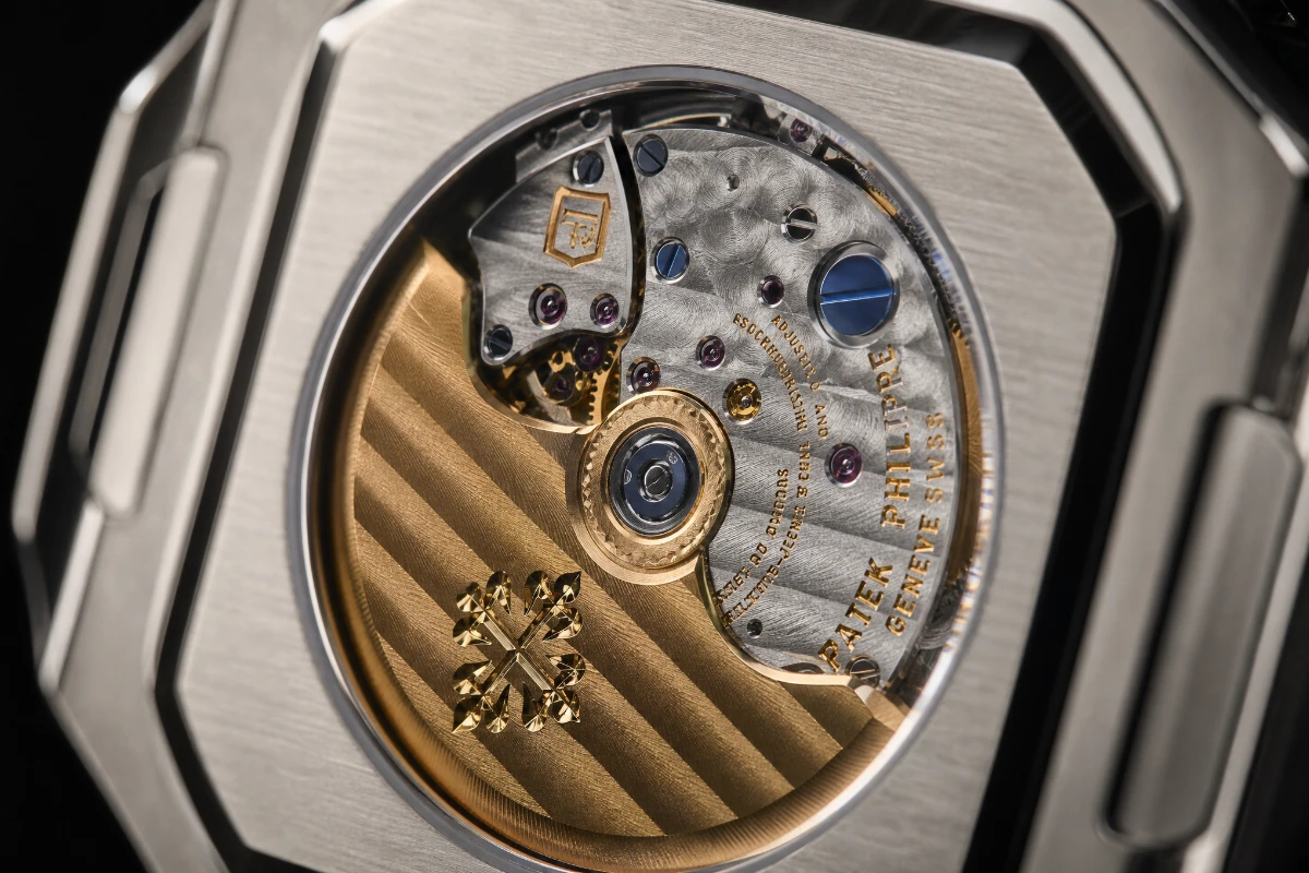 Close-up of a hand-finished Patek Philippe watch movement showing Cotes de Geneve stripes, perlage, bevelled bridges and blued screws